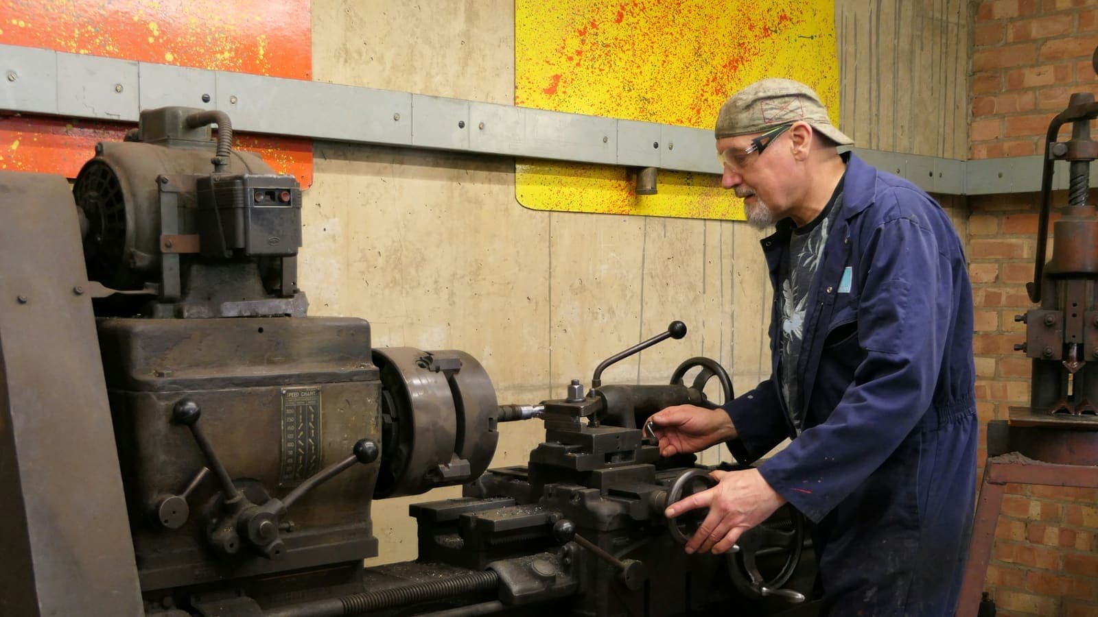 Un tourneur au travail sur un tour conventionnel ancien.